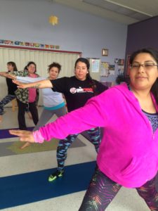 Women in the yoga class hold warrior poses.